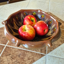 Large handmade ceramic fruit bowl styled with red apples on a warm dining table